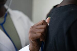 Photo of a GP using a stethoscope to check a patient.