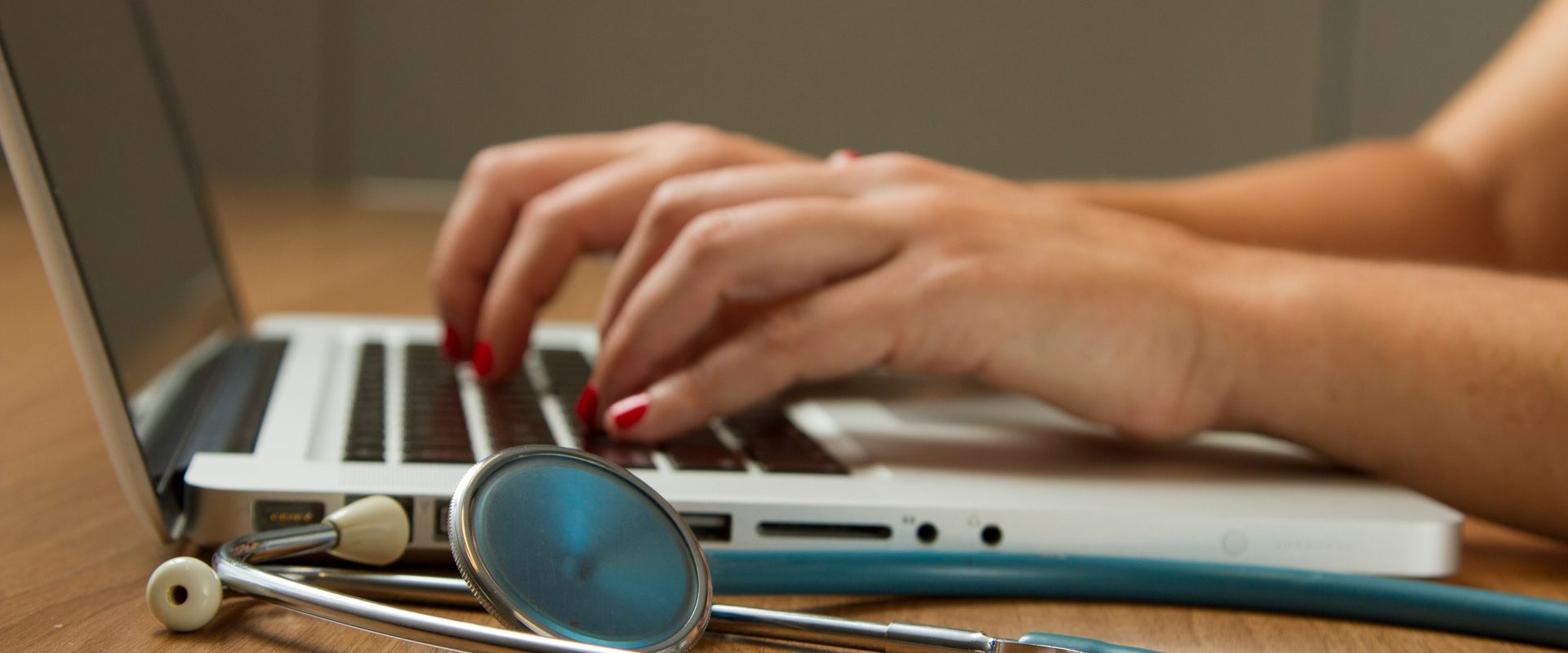 Stock image of a doctor typing on a laptop