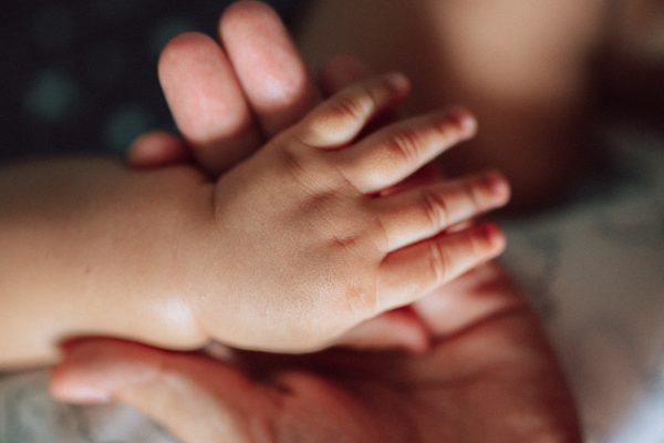 Stock image of a mother holding the hand of her newborn baby